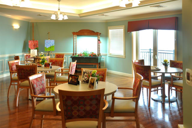 A cozy and well-decorated living room with tables, chairs, and ample lighting.