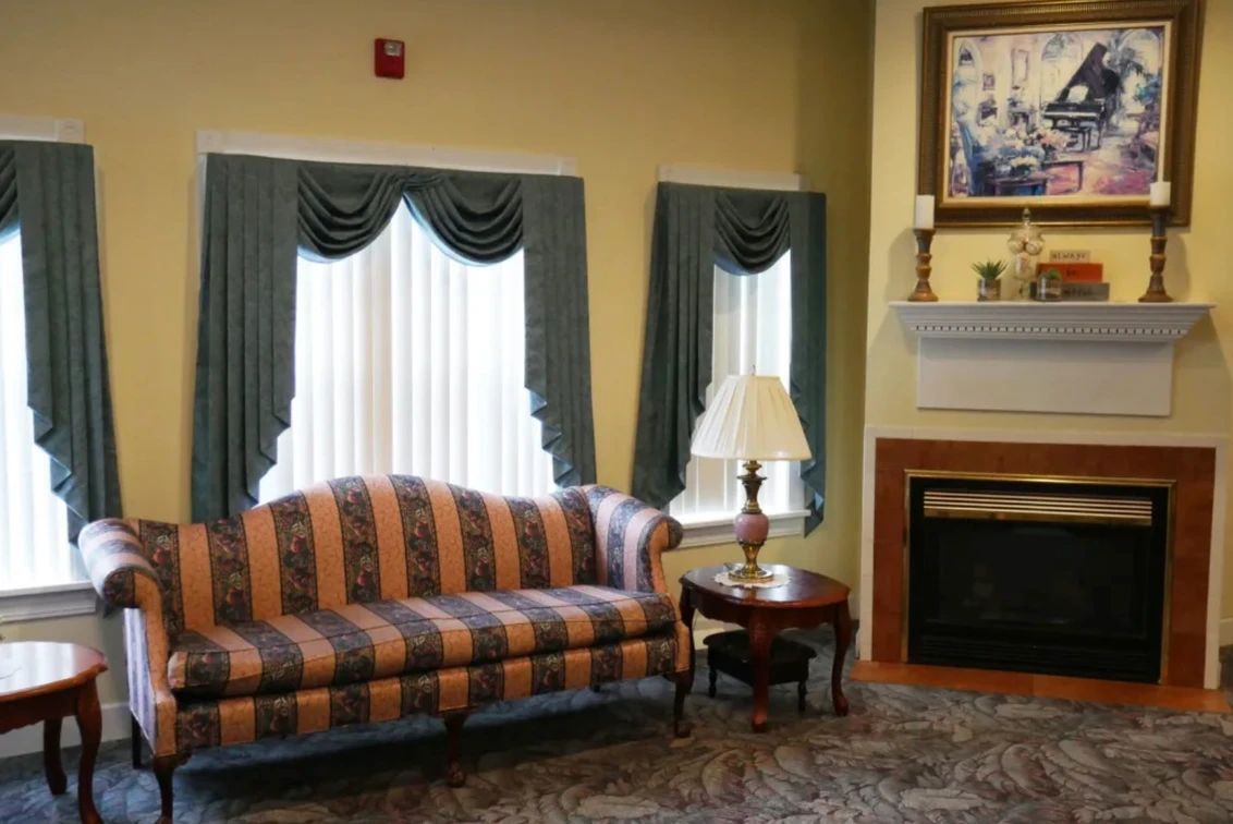 A traditional living room with a striped sofa, elegant curtains, and a cozy fireplace.