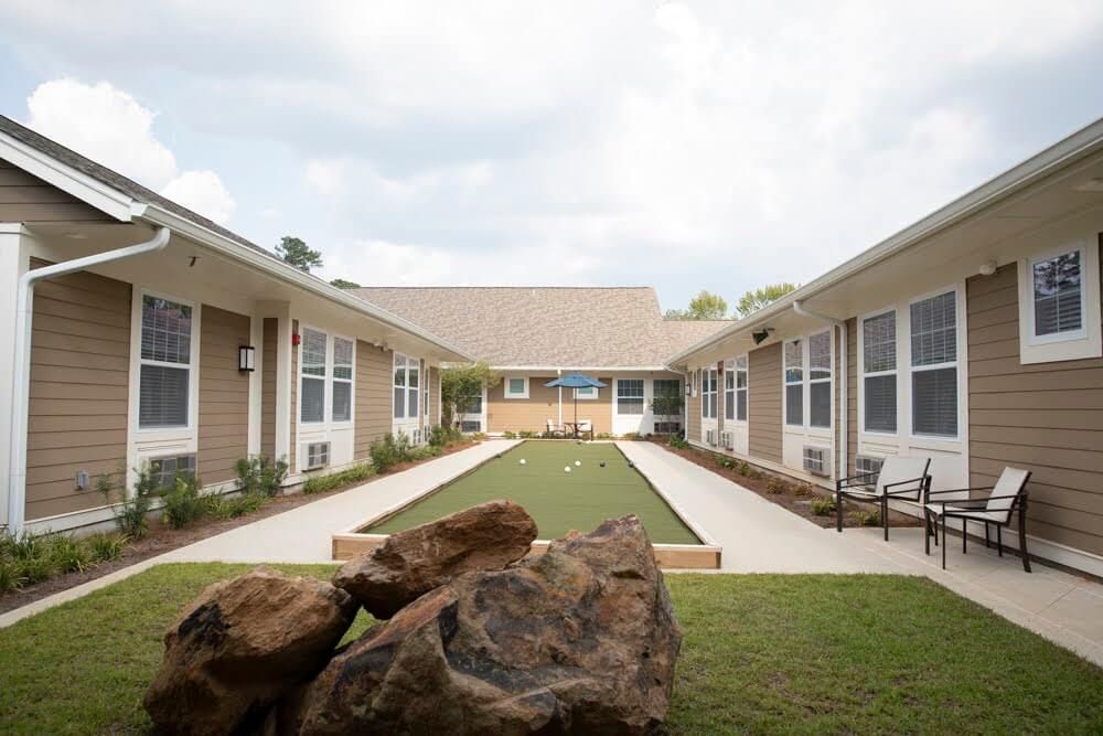 A serene courtyard with a central pathway flanked by buildings and greenery.