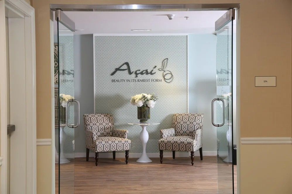 A welcoming lobby with two patterned chairs, a small white table with flowers, and a sign on the wall.
