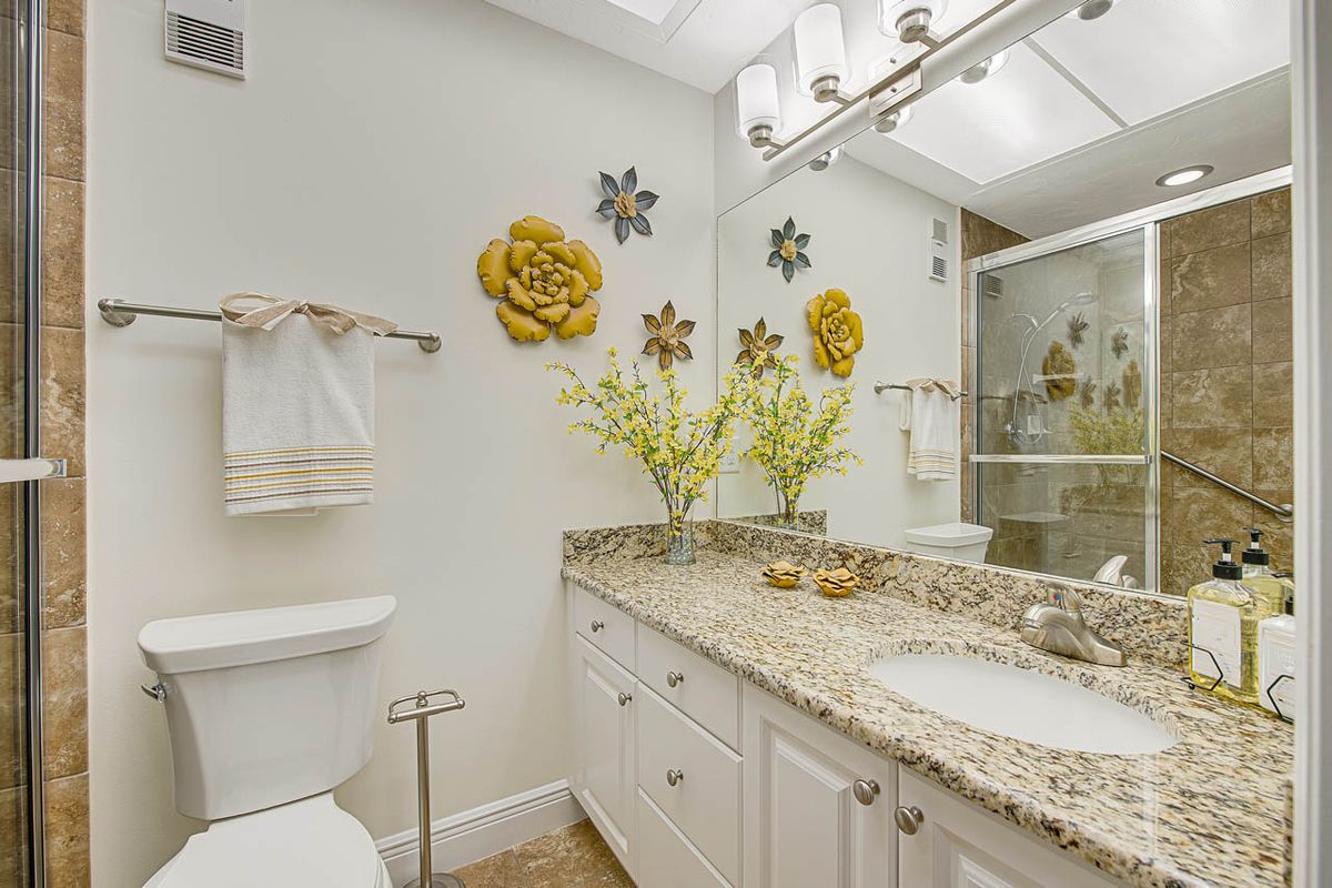 A well-decorated bathroom with a granite countertop, mirror, and floral decorations.