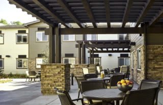 A stylish outdoor patio area with tables and chairs under a pergola.