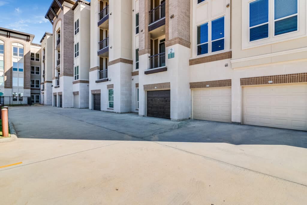 A modern apartment complex with multiple garage doors and large windows.