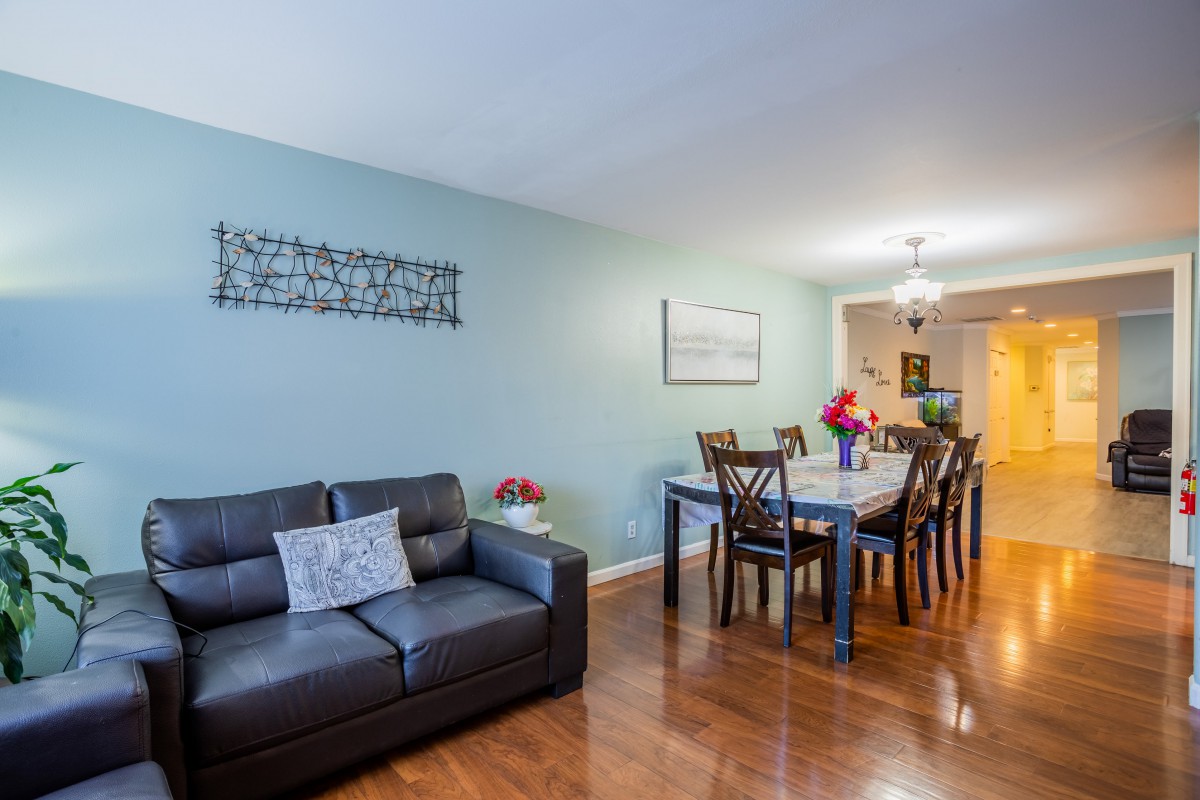 A cozy living and dining area featuring a dark sofa, elegant dining set, and decorative wall art.