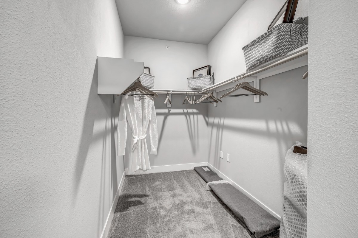A minimalist walk-in closet with shelving and hangers.