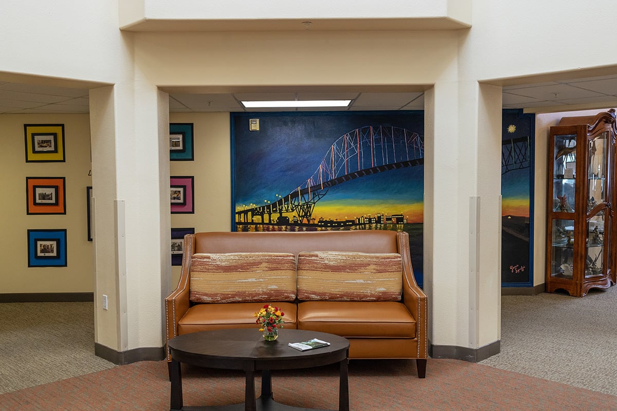 A cozy lobby area featuring a leather couch, a small round table, and a colorful mural on the wall.