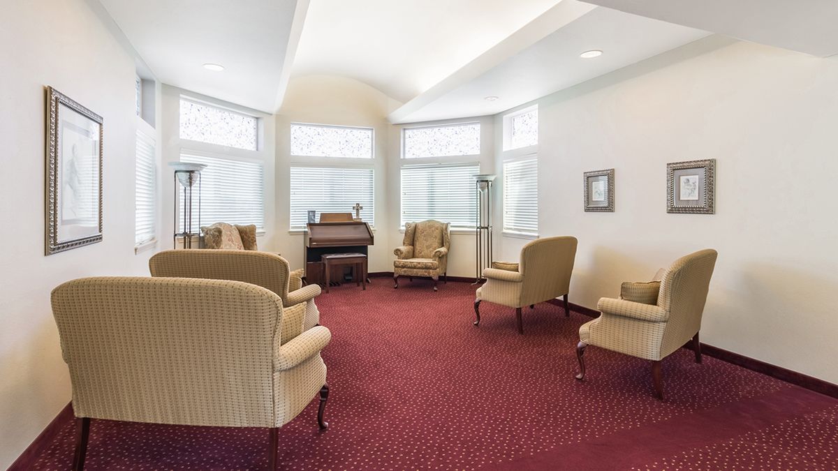 A cozy living room with a piano, surrounded by comfortable chairs and large windows.