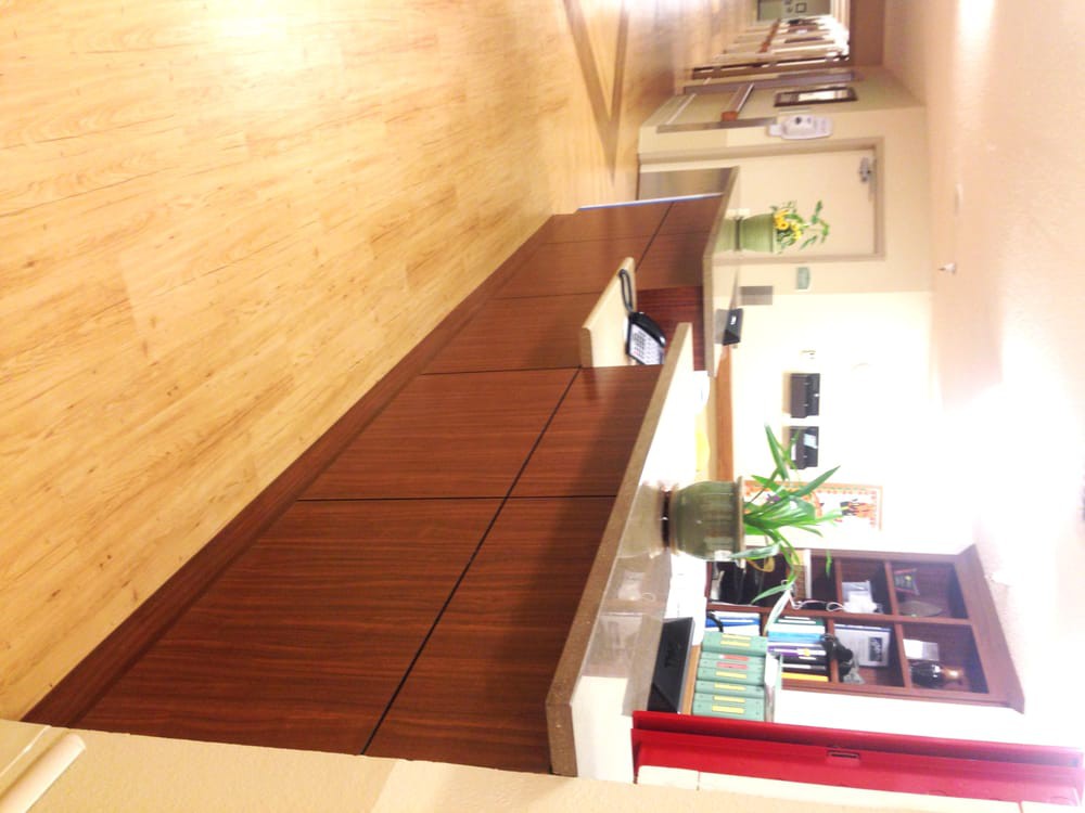 A reception desk in an office setting with plants and bookshelves.