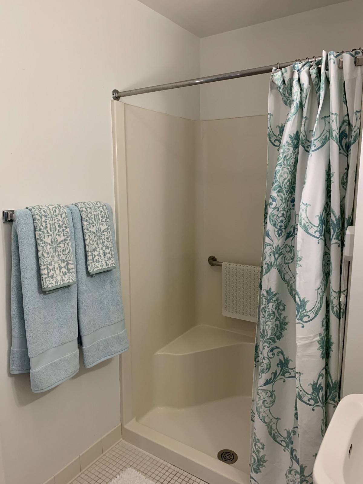 A bathroom with a shower featuring a patterned curtain and neatly hung towels.