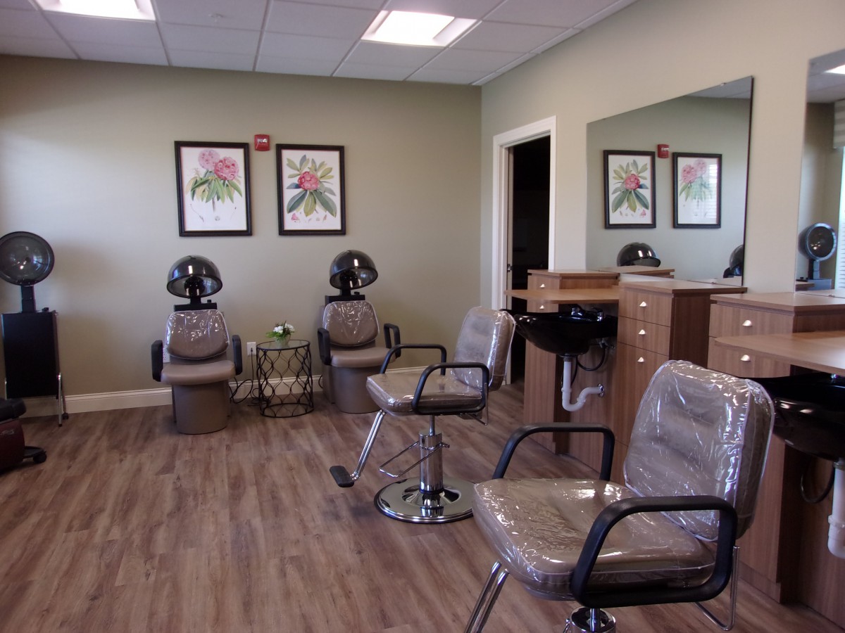 An empty hair salon with chairs, mirrors, and hair dryers.