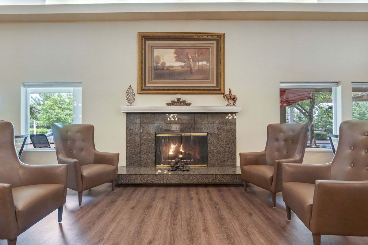 A cozy living room featuring a fireplace flanked by two armchairs and adorned with framed artwork above.
