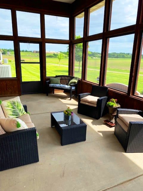 A cozy sunroom with comfortable seating and expansive views of the outdoors.
