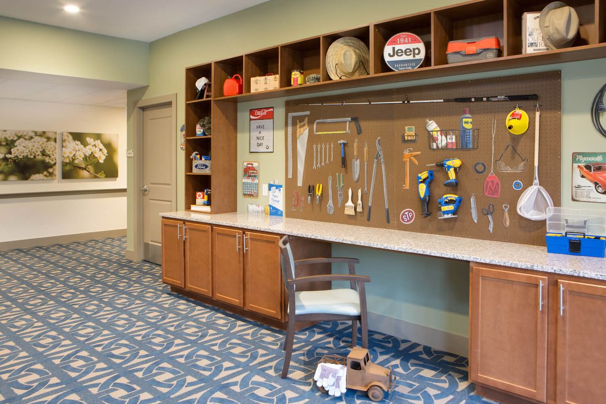 A workshop area featuring a variety of tools displayed on a board, with cabinets and shelves containing various items and toys.