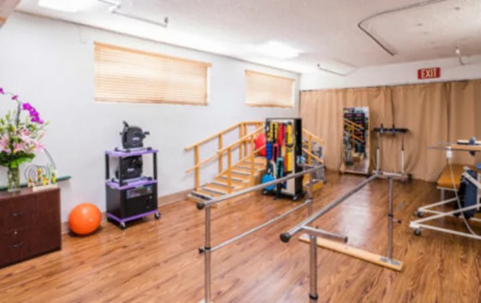 A rehabilitation room equipped with parallel bars and various physical therapy tools.