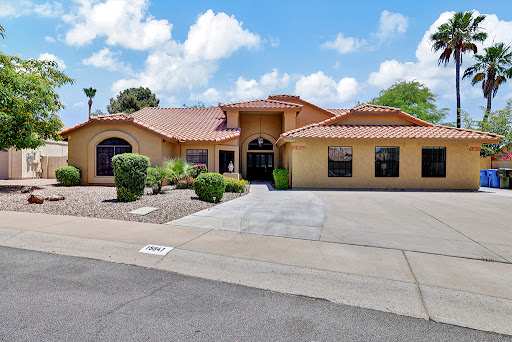 A beautiful residential home with a landscaped front yard under a bright blue sky.