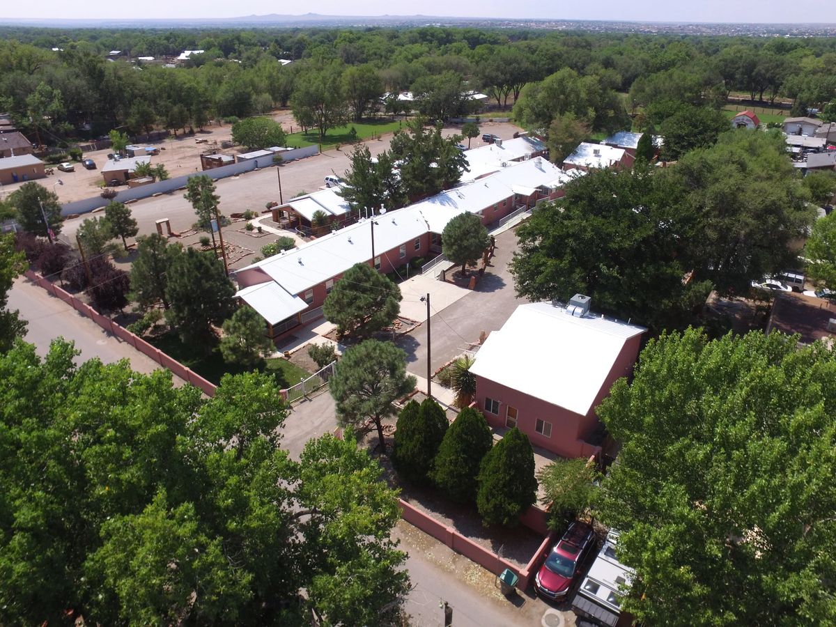 Aerial view of a residential area with buildings, surrounded by trees and roads.