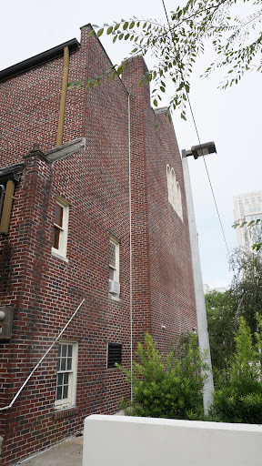 A view of a brick building featuring windows and a ladder against its facade.