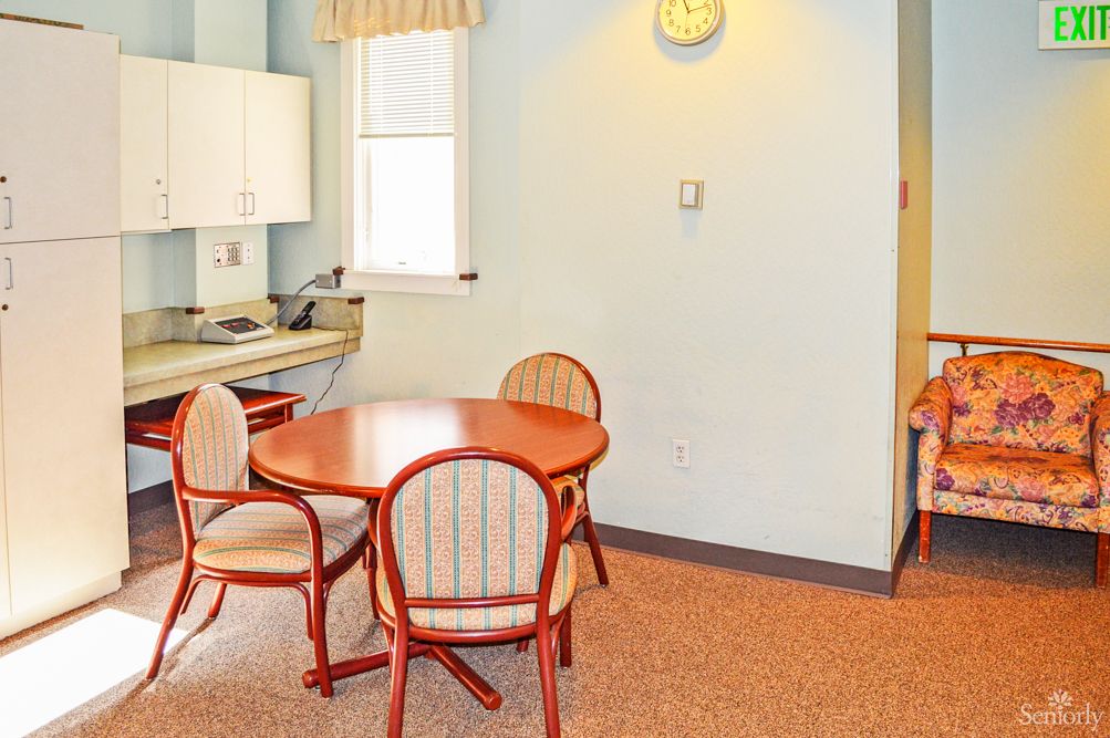 A cozy dining area with a round wooden table and chairs near a kitchenette.