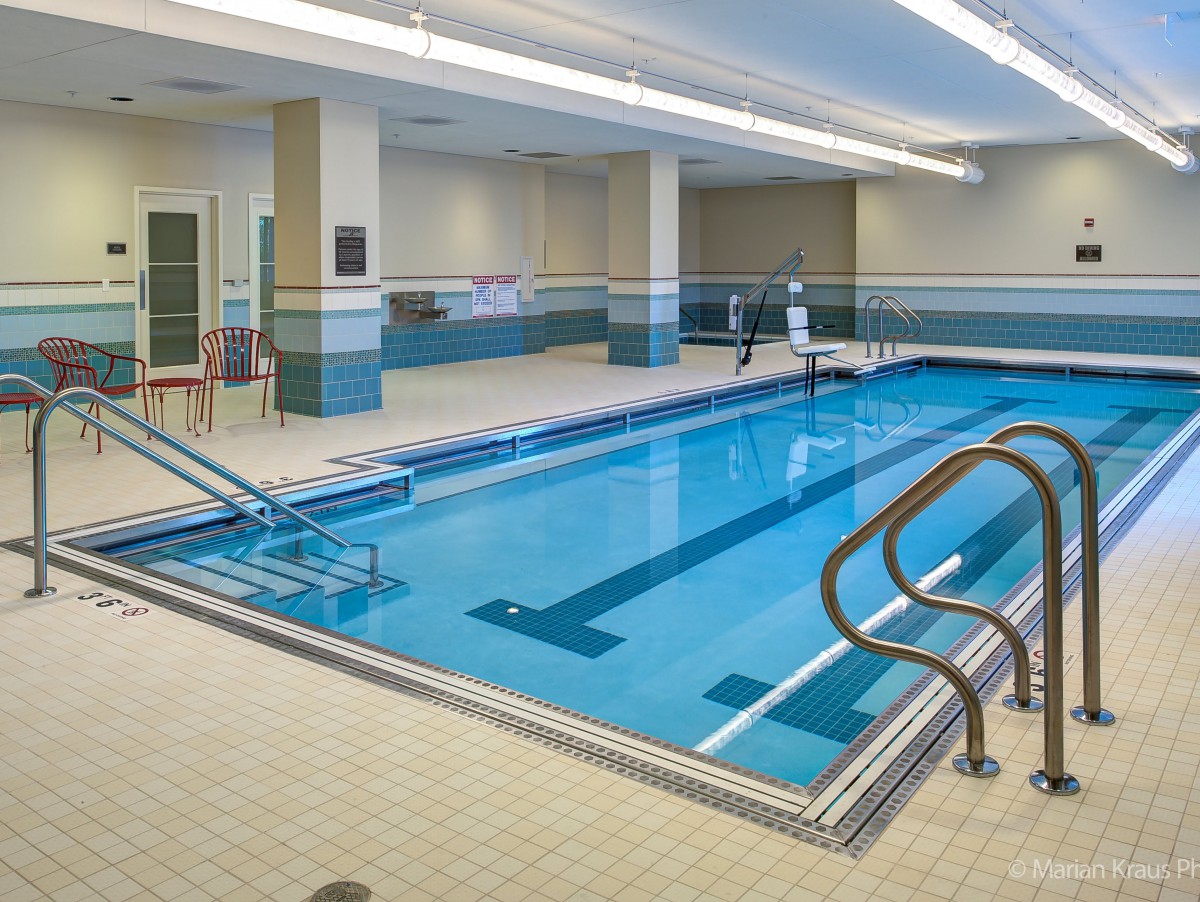 An indoor swimming pool with a tiled deck and water exercise equipment.