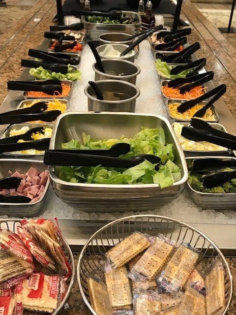 A well-stocked salad bar with a variety of fresh vegetables and toppings.