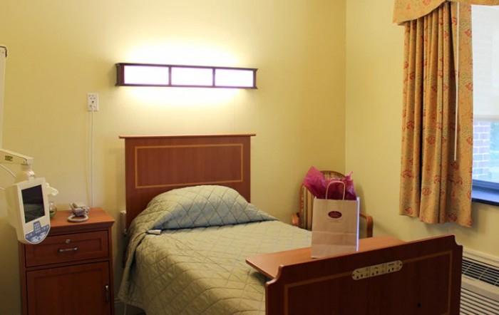 A minimalist bedroom with a single bed and wall-mounted lamp.