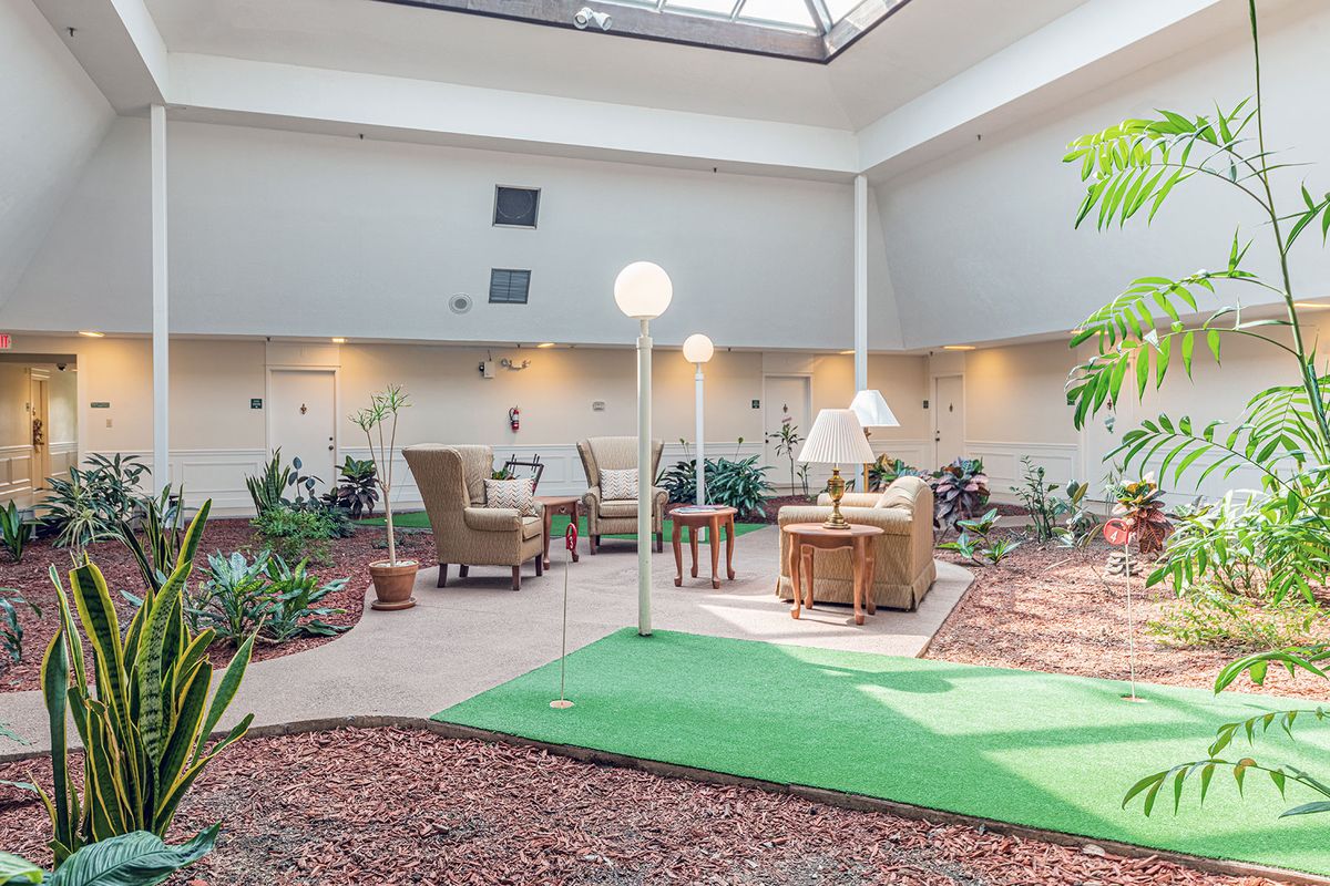 A spacious indoor lounge area featuring comfortable seating, abundant plants, and natural lighting.