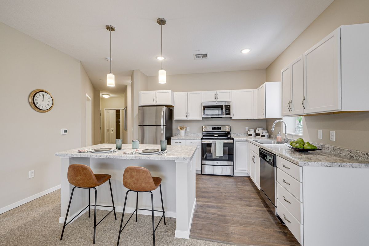A modern kitchen with white cabinets, stainless steel appliances, and a center island with bar stools.