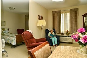 A senior person sits in a comfortable armchair in a cozy living room.