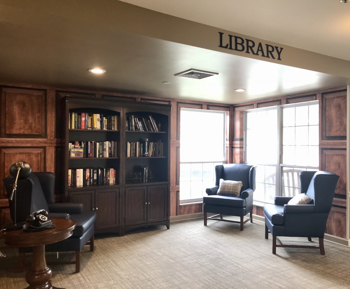 A cozy library corner with comfortable seating and a bookshelf filled with books.