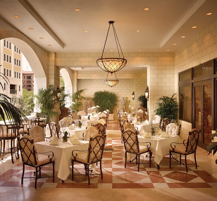 Elegant restaurant interior with neatly arranged tables and lush greenery.