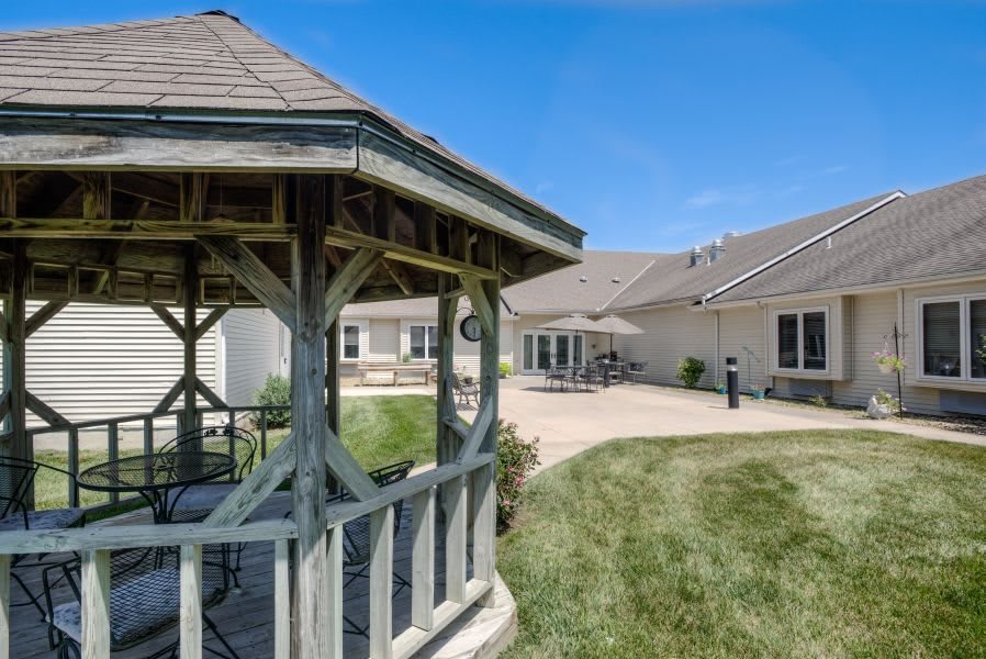 A scenic outdoor area with a wooden gazebo and a modern building in the background.