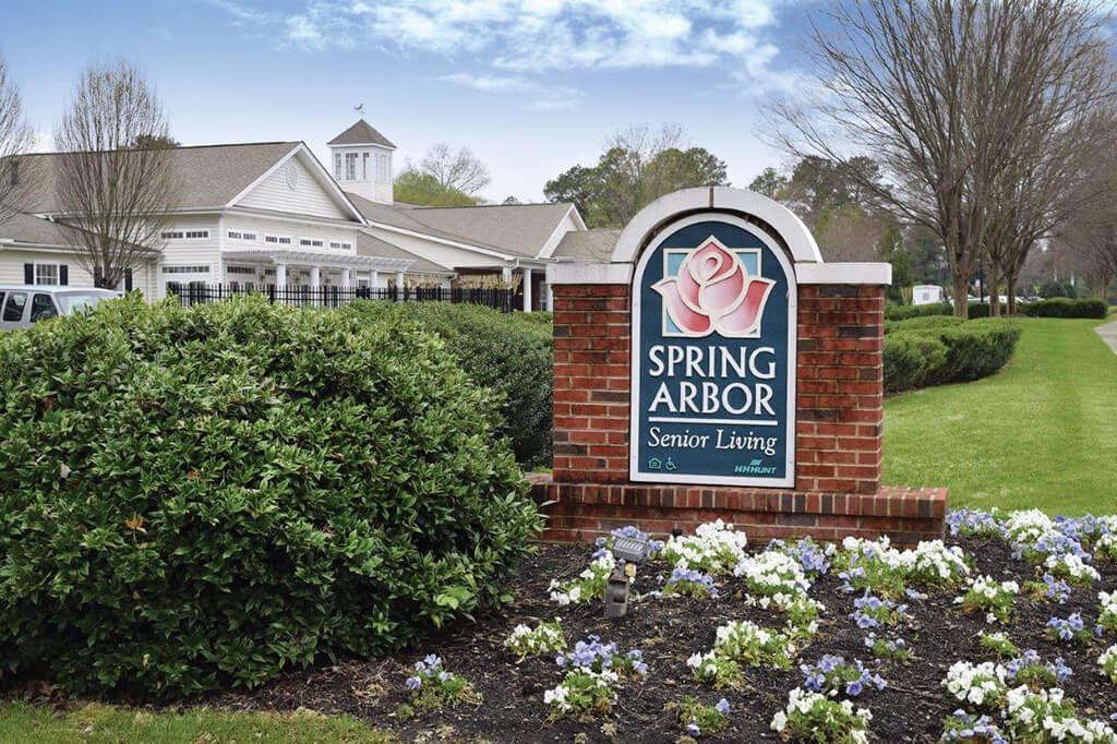 Entrance sign for Spring Arbor Senior Living surrounded by greenery and flowers.