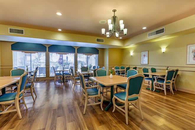 A spacious and elegantly designed dining area with teal chairs and wooden tables.