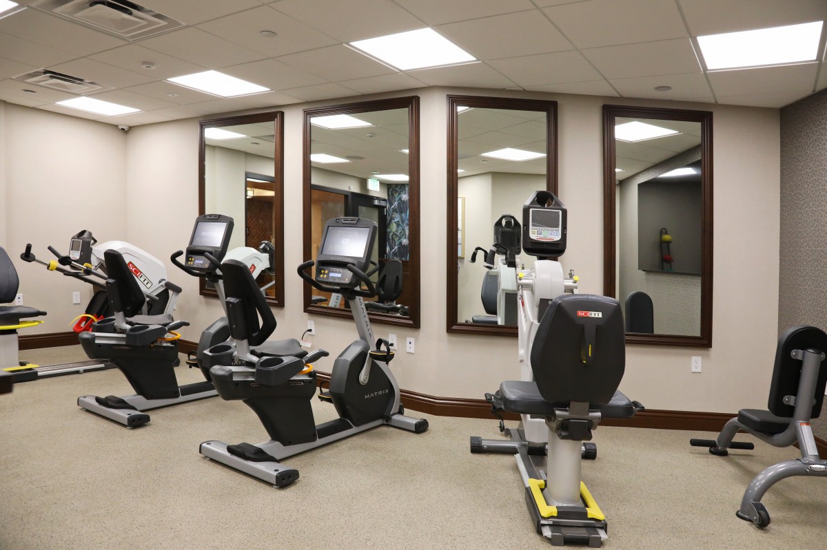 A modern fitness center with stationary bikes and mirrors.