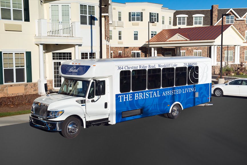 A blue and white shuttle bus parked on a street in front of buildings.
