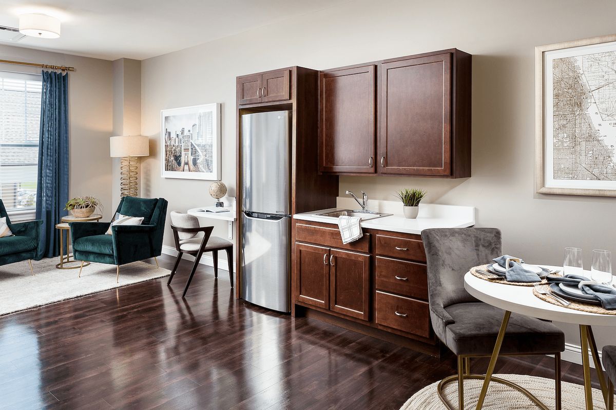A modern living room and kitchen area with dark wood cabinets and hardwood flooring.