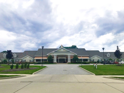 A modern healthcare facility surrounded by well-maintained landscaping under a cloudy sky.