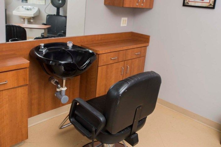 A salon setup featuring a styling chair and washbasin.