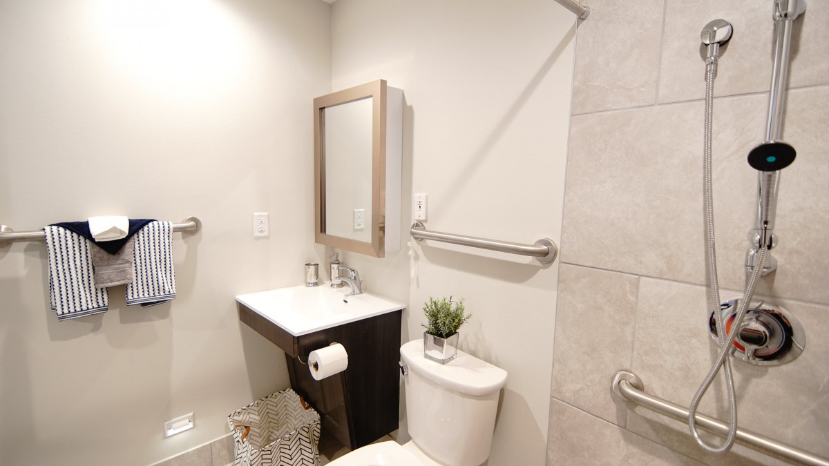 A minimalist bathroom with a sink, mirror, and toilet featuring simple decor.