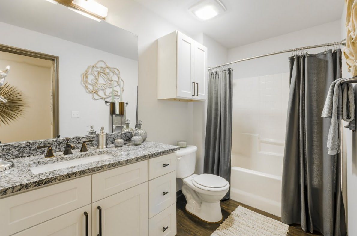 A modern bathroom featuring a sink, toilet, and shower with a curtain.