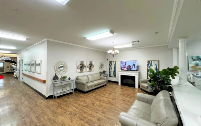 A cozy living room with modern decor featuring sofas, a TV above a fireplace, and wooden flooring.