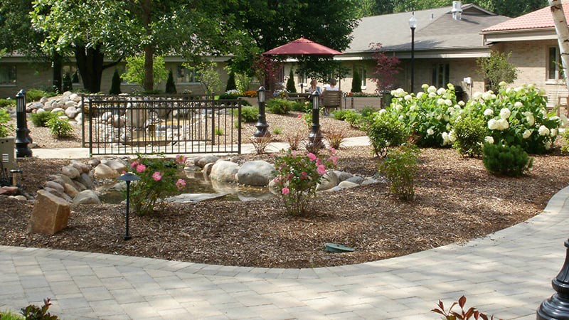 A beautifully landscaped garden with a pathway, flowers, and outdoor seating area.