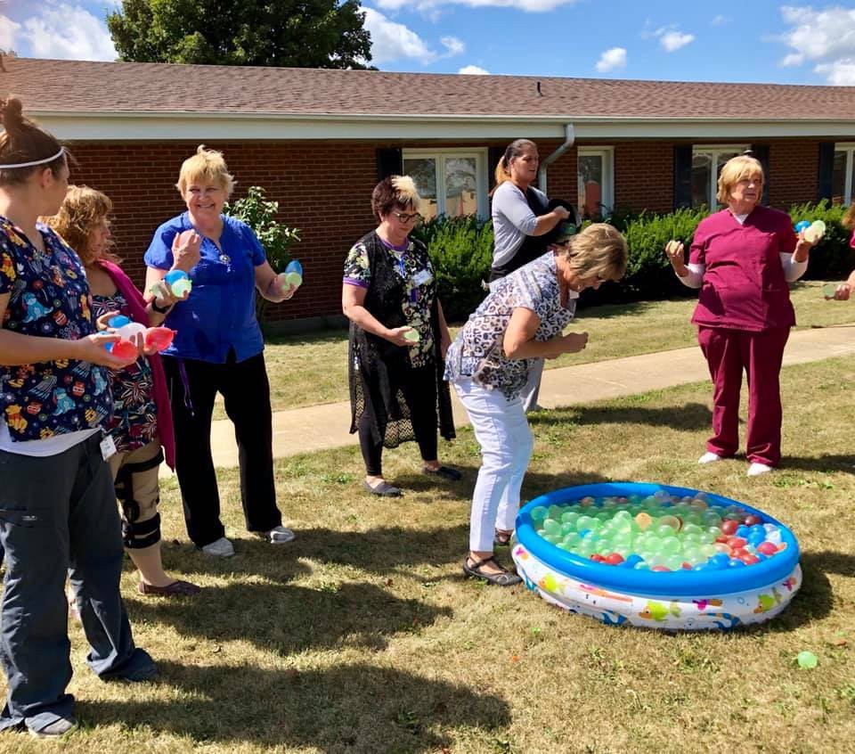 A group of people enjoying an outdoor activity with a small pool filled with colorful items.