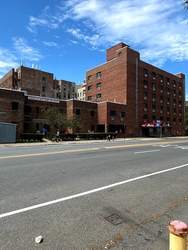 A brick building situated in an urban setting, viewed from the street under a partly cloudy sky.