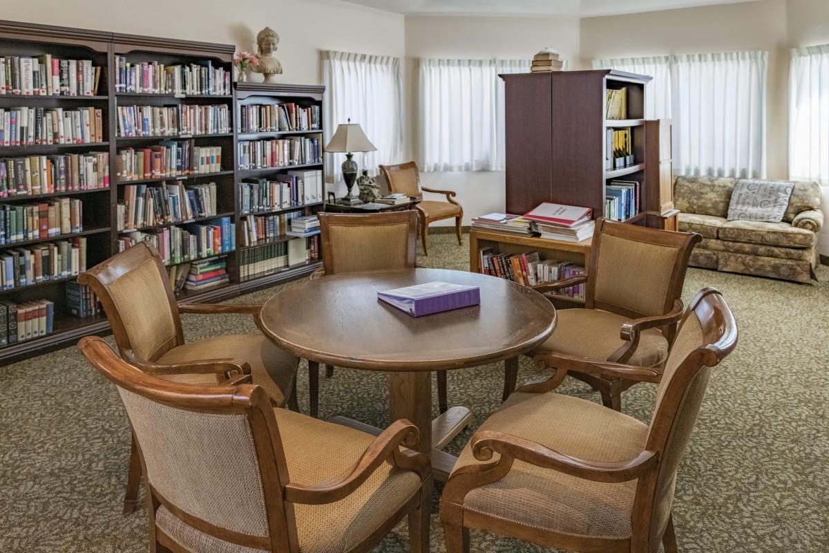 A cozy reading area in a library with bookshelves and seating around a table.