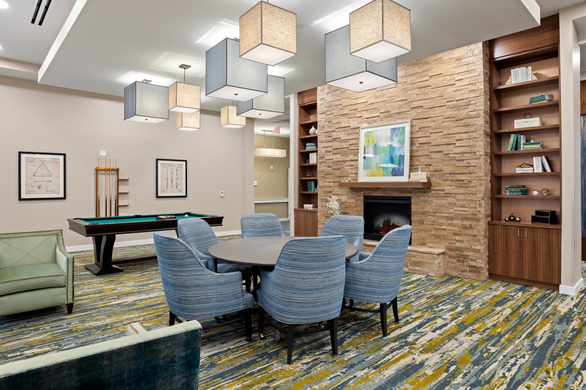 A modern living room with a round table, chairs, and a fireplace.