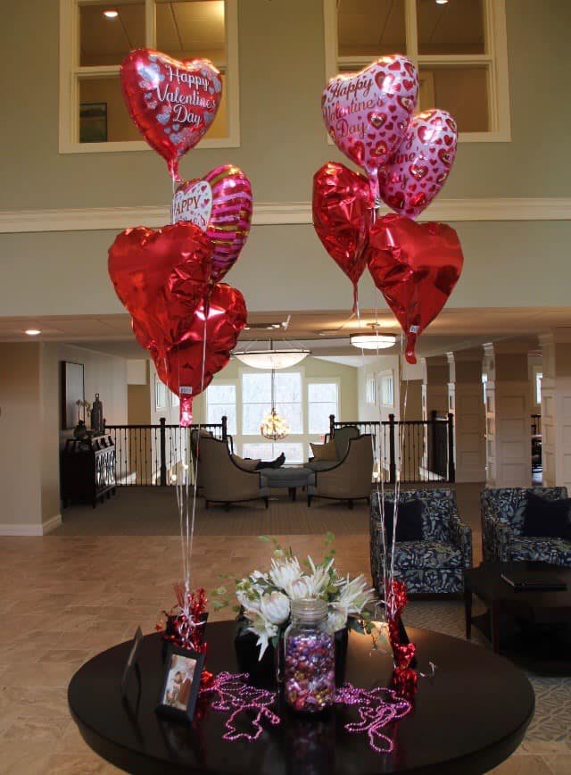 Red and pink heart-shaped balloons arranged in a lobby area.