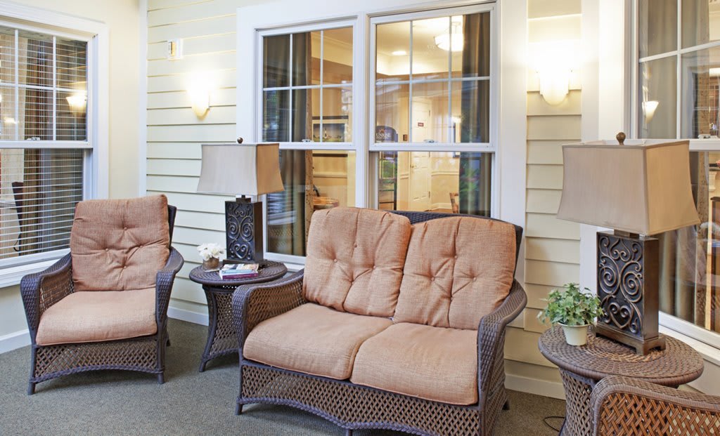 A cozy porch area with cushioned wicker chairs, a small table, and ambient lighting.