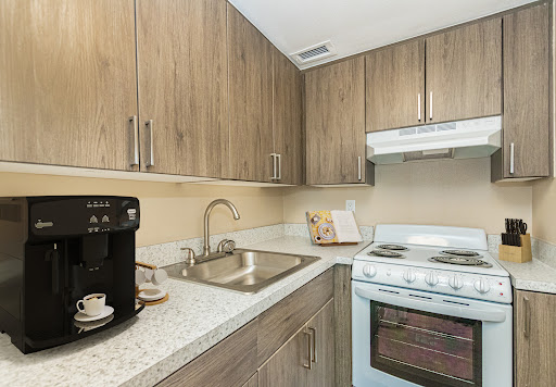 A modern kitchen featuring wooden cabinets, a stainless steel sink, and essential appliances.