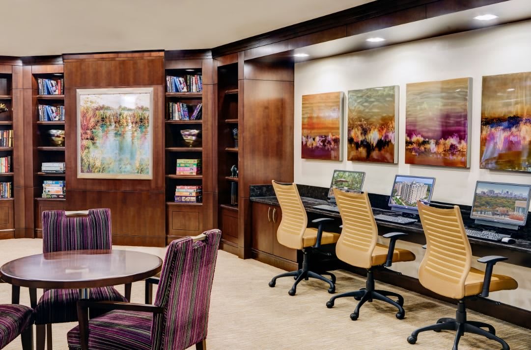 A modern office space with computers, bookshelves, and a meeting area featuring contemporary artwork.